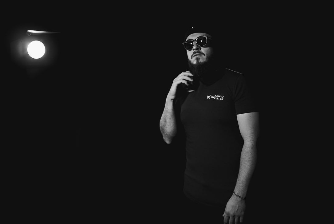 DJ Deivid Xister de óculos escuros sob luz de estúdio