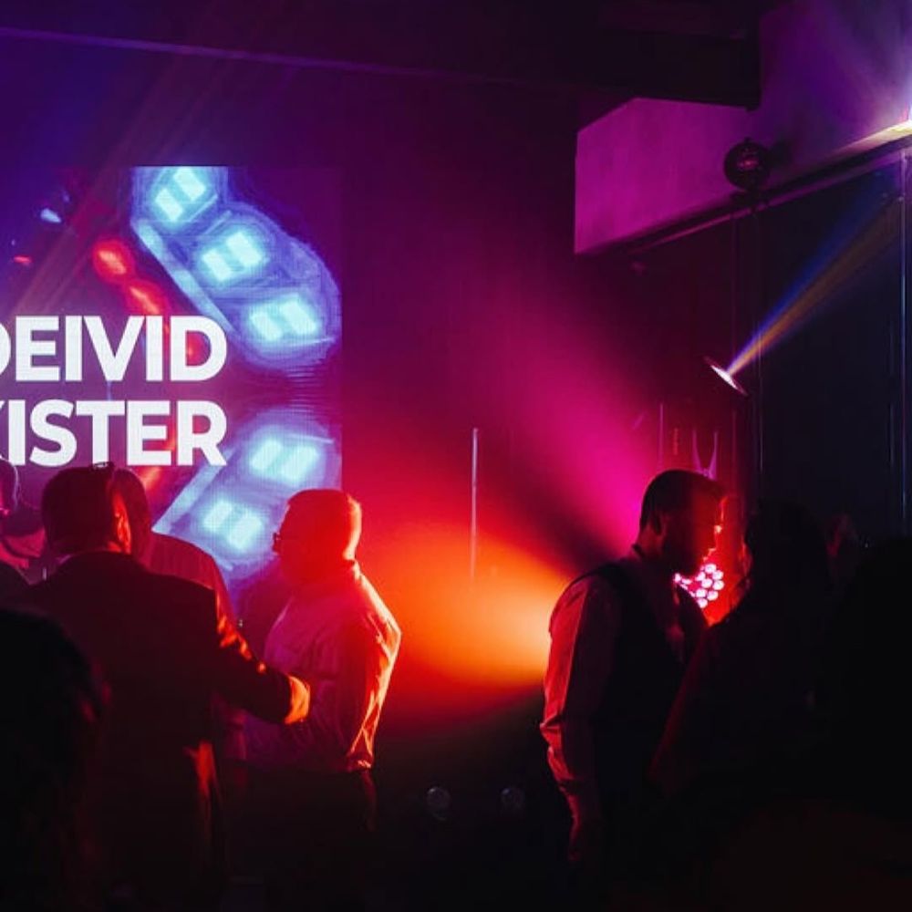 Convidados na pista com iluminação rosa e painel de LED